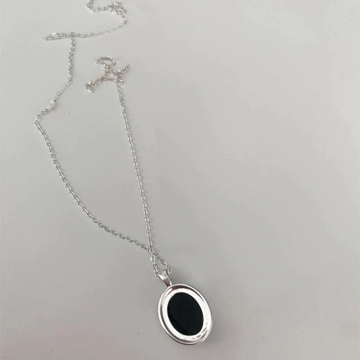 Silberne Halskette mit ovalem schwarzem Anhänger, eleganter Schmuck, Damenaccessoire.