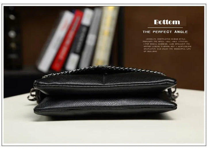 Schwarze Lederhandtasche mit Kettendetail, elegant, modern, für Damen, auf Bücherregal-Hintergrund.