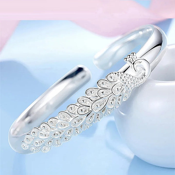 Silbernes Pfauenarmband, elegantes Design, Schmuck für Damen, modisches Accessoire.
