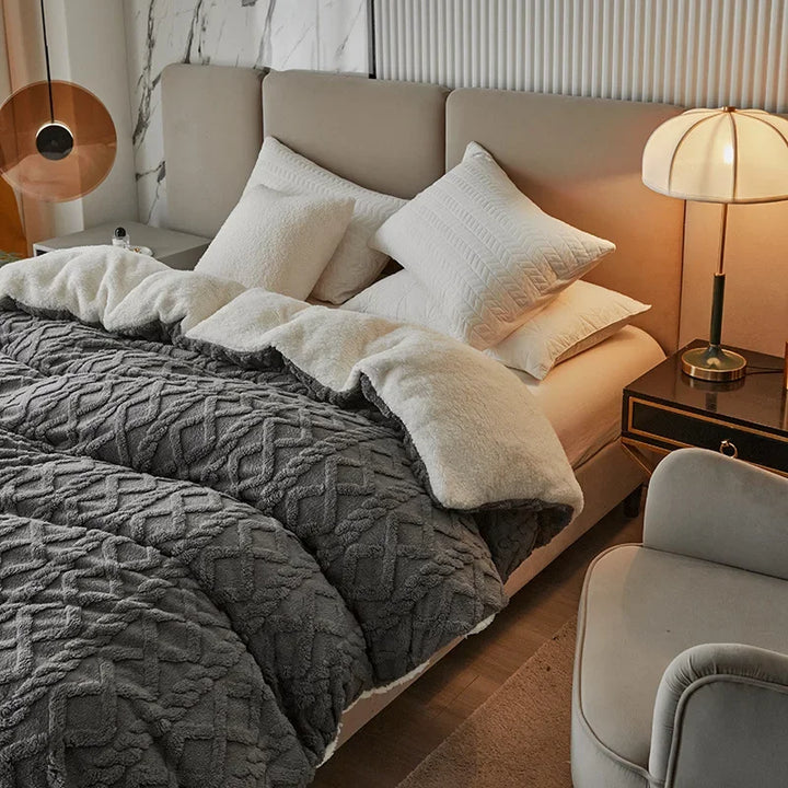 Graues Bett mit weißer Bettwäsche, Kissen und Nachttischlampe in modernem Schlafzimmer.