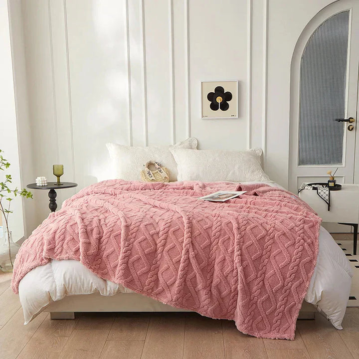 Rosa Strickdecke auf weißem Bett, gemütliches Schlafzimmer, moderne Inneneinrichtung.