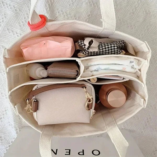 Beige Canvas-Tasche, gefüllt mit Kosmetiktasche, Wasserflasche, Geldbörse und Accessoires.
