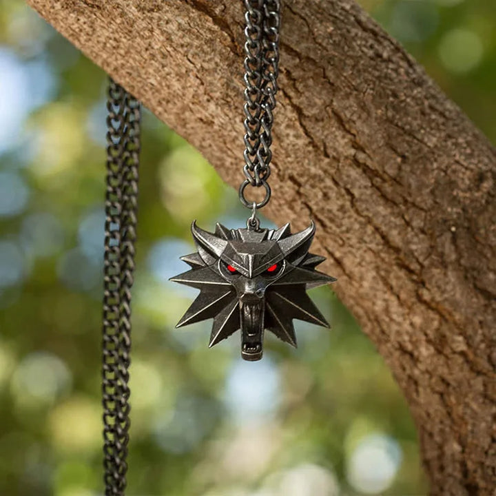 Silberne Wolfskopf-Halskette mit roten Augen, hängend an Ast, Schmuck für Fantasy-Fans.