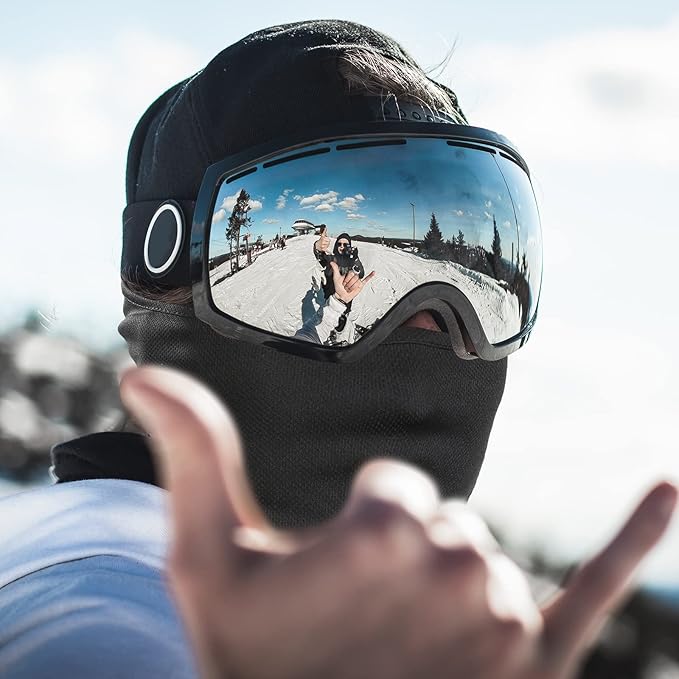 Schwarze Skibrille mit verspiegeltem Glas, reflektiert Schneelandschaft, Wintersportzubehör.