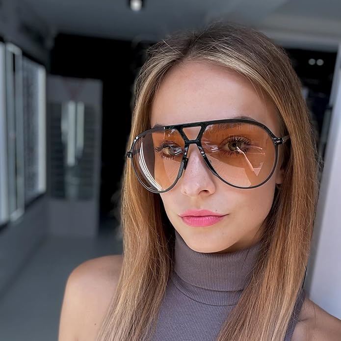 Frau mit übergroßer, modischer Sonnenbrille, orange getönt, schwarzer Rahmen, Innenraum.