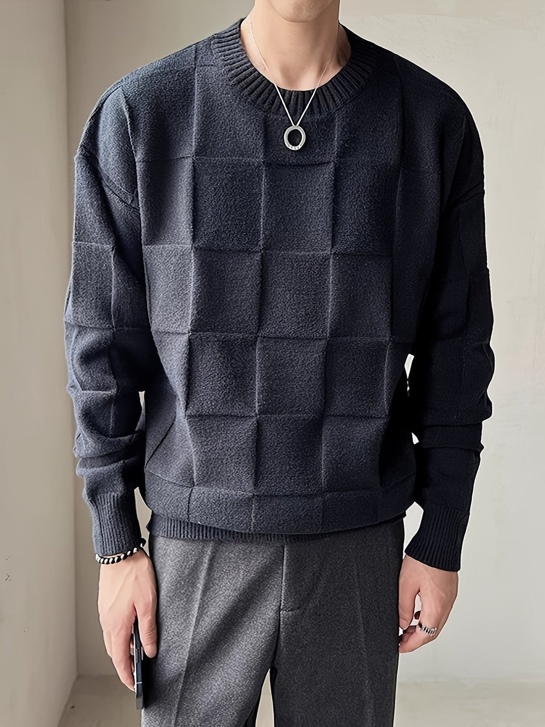 Mann in schwarzem, kariertem Pullover, elegantes Design, Herbstmode, Herrenbekleidung.