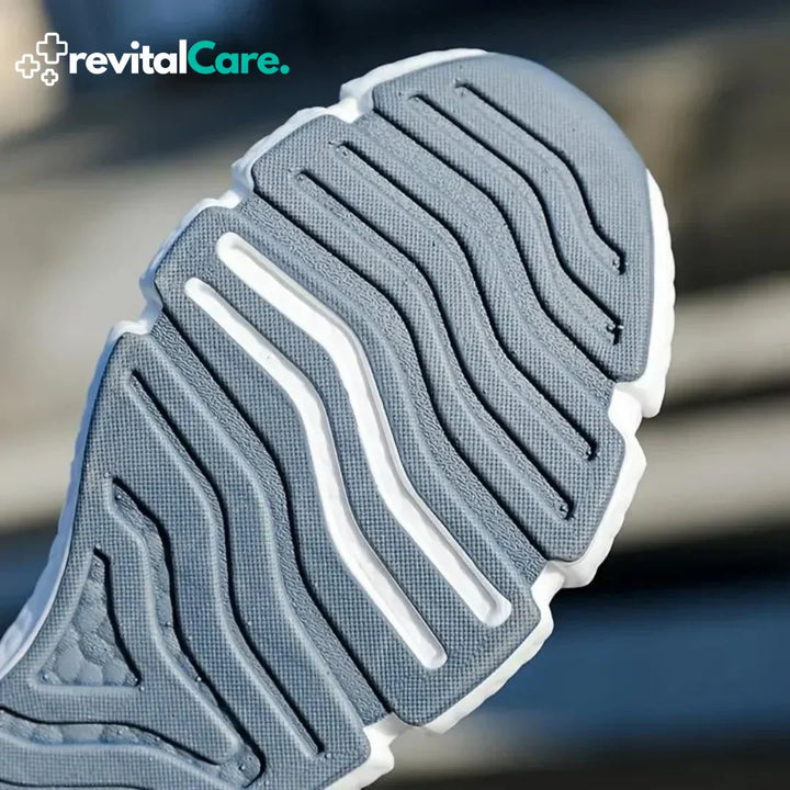 Graue Sportschuhsohle mit rutschfestem Profil, Nahaufnahme, RevitalCare-Logo.