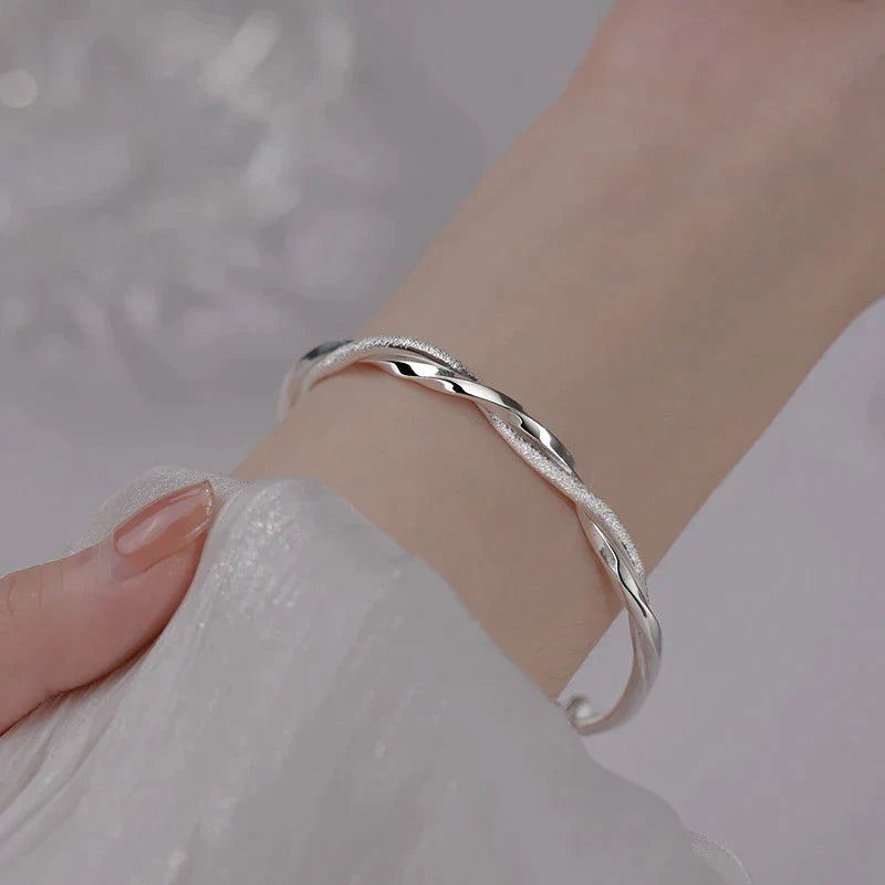 Silbernes Armband, gedrehtes Design, eleganter Schmuck, Damenarmband, modisches Accessoire.