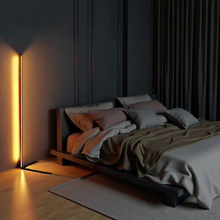 Lampa svítící oranžově v tmavé ložnici u nízké postele s polštáři a závěsem 2