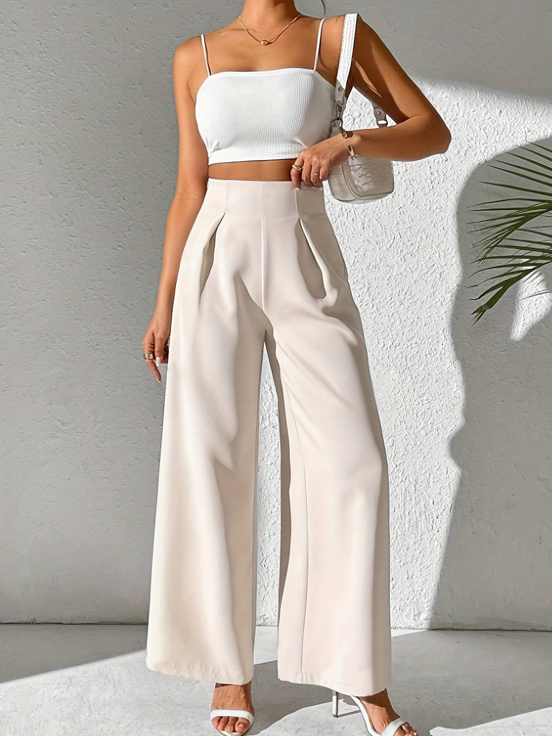 Frau in weißem Crop-Top und beigen High-Waist-Hosen, Sommermode, eleganter Look.