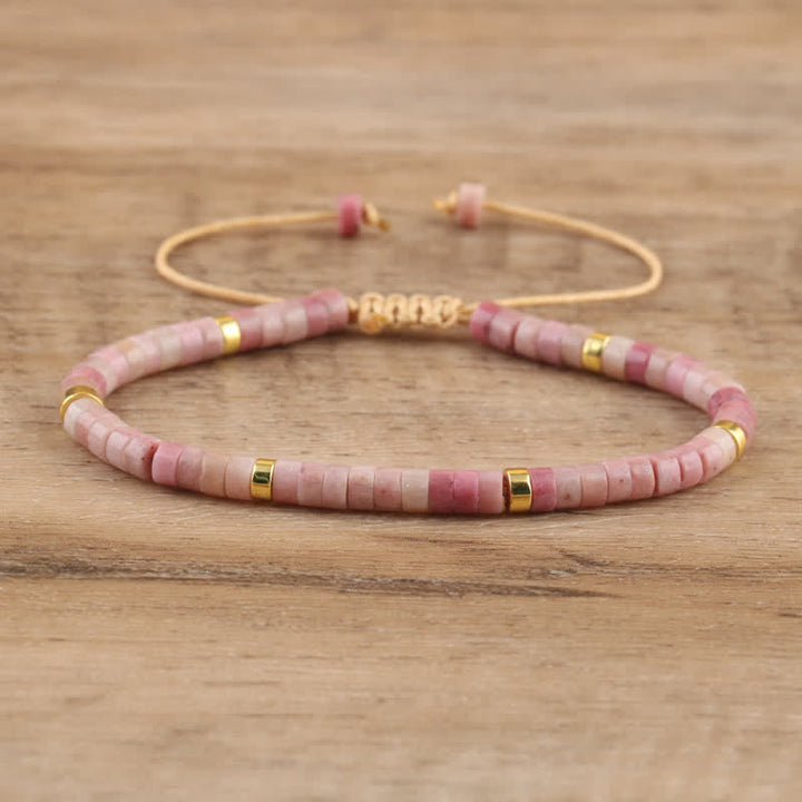 Rosa Perlenarmband mit goldenen Akzenten auf Holzoberfläche, handgefertigter Schmuck.