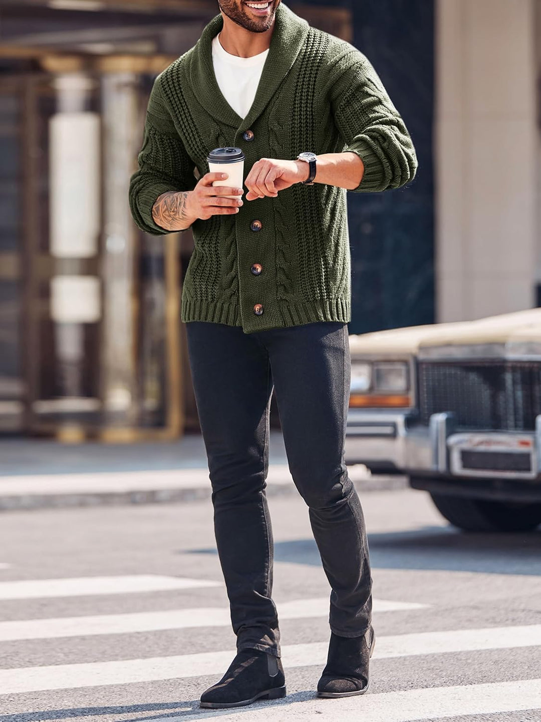 Mann in grünem Strickcardigan mit Kaffeebecher, schwarze Hose, städtische Straße.