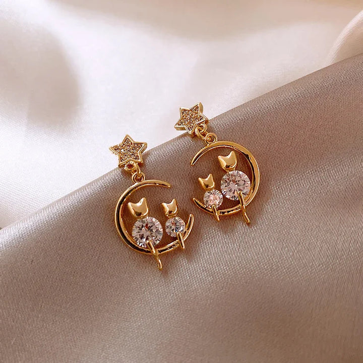 Goldene Ohrringe mit Stern- und Mondmotiv, Katzen-Design, funkelnde Kristalle, elegant, modisch.