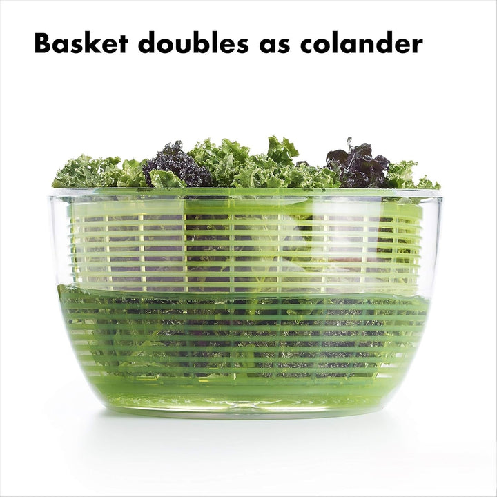 Transparente Salatschleuder mit grünem Sieb, gefüllt mit frischem Salat, Kunststoff, multifunktional.