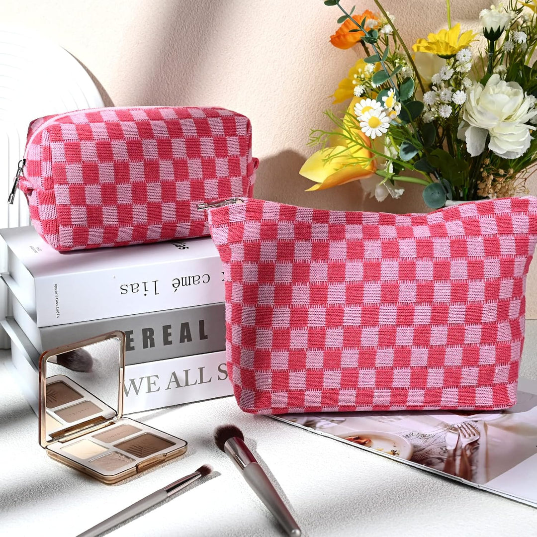 Rosa karierte Kosmetiktasche aus Stoff, neben Blumen und Make-up-Pinsel auf einem Tisch.