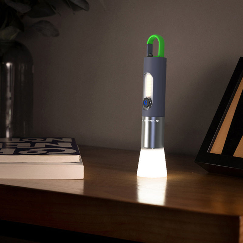 Schwarze LED-Taschenlampe mit grünem Haken auf Holztisch, modernes Design, Nachtlicht.