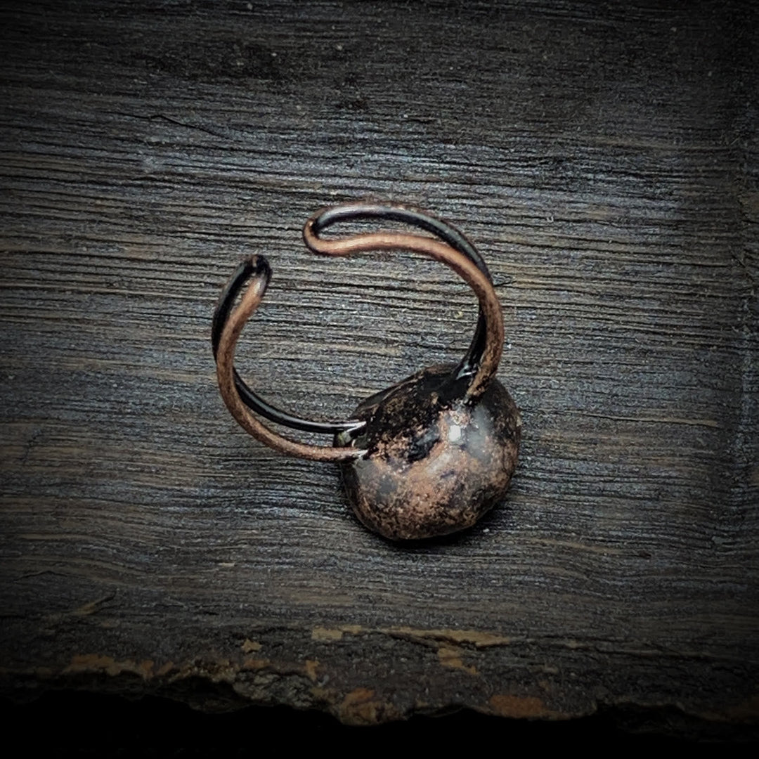 Antiker bronzener Ring auf Holzoberfläche, rustikales Schmuckdesign, Vintage-Stil.