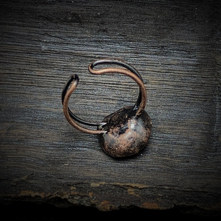 Antiker bronzener Ring auf Holzoberfläche, rustikales Schmuckdesign, Vintage-Stil.