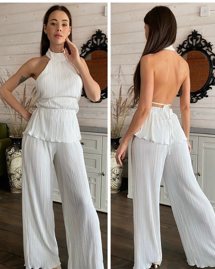 Frau in weißem, ärmellosem, plissiertem Jumpsuit mit offenem Rücken, elegantes Design.