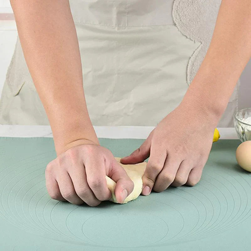 Person knetet Teig auf grüner Silikon-Backmatte, ideal für Backen und Teigzubereitung.