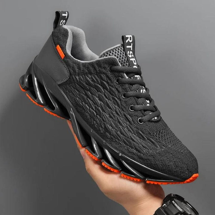 Schwarzer Sportschuh mit orangen Akzenten, atmungsaktives Mesh, rutschfeste Sohle.