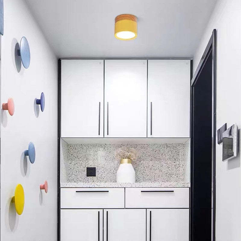 Weiße moderne Küche mit bunten Wandhaken, gelber Deckenleuchte, minimalistisches Design.
