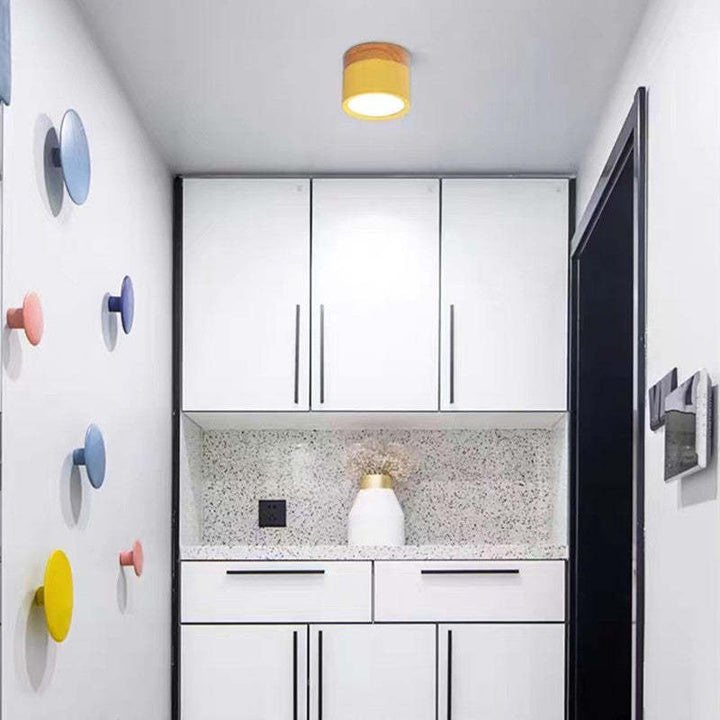 Weiße moderne Küche mit bunten Wandhaken, gelber Deckenleuchte, minimalistisches Design.