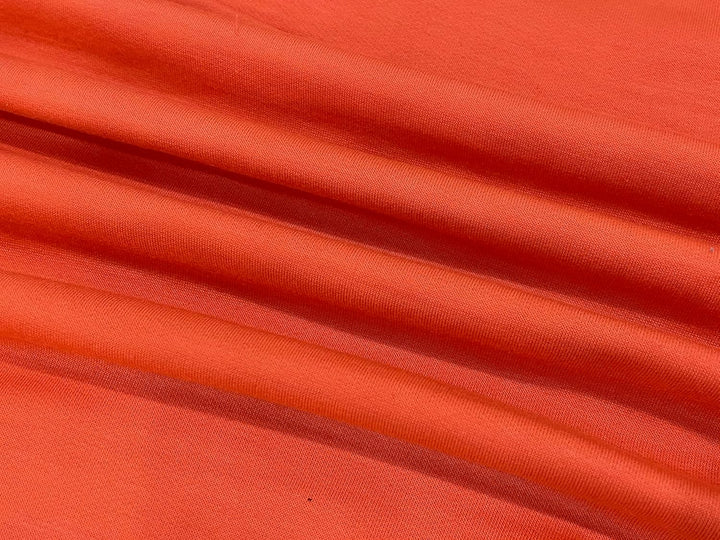 Orangefarbener Baumwollstoff, weicher Textilstoff, ideal für Kleidung und Dekoration.