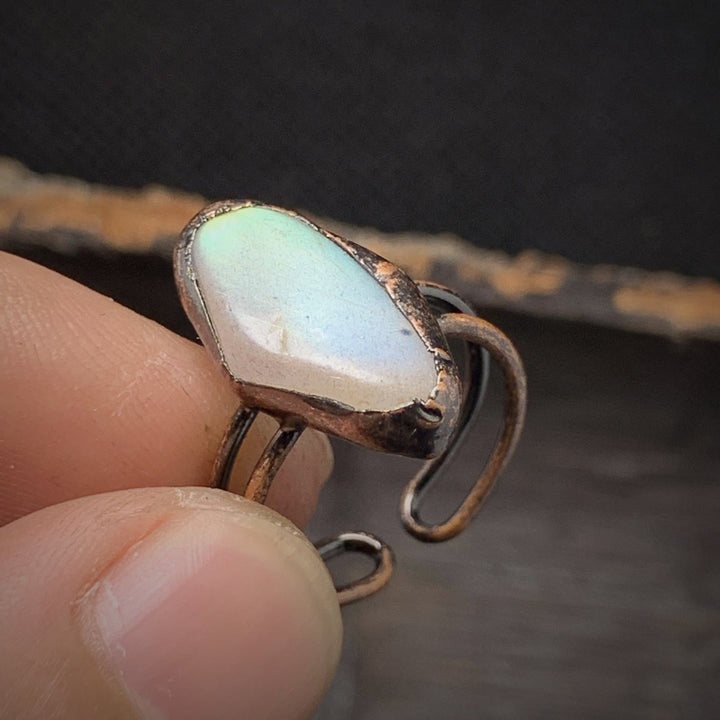 Handgefertigter Ring mit weißem Opalstein und Kupferfassung, einzigartiges Schmuckdesign.