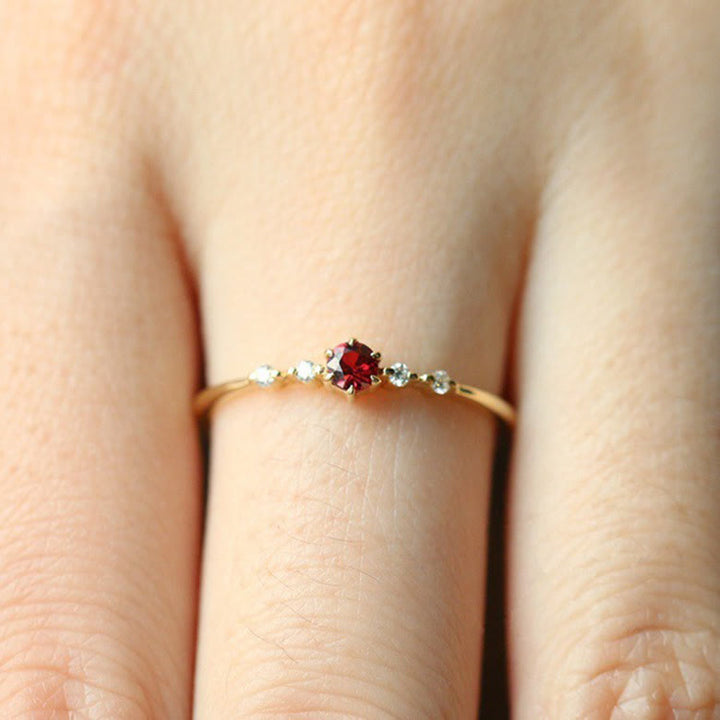 Dünner Goldring mit rotem Edelstein und kleinen Diamanten, eleganter Schmuck für Damen.