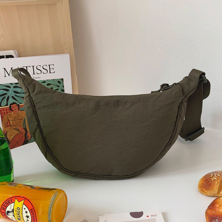Olivgrüne Umhängetasche aus Stoff auf Tisch, modisch, praktisch, ideal für Alltag und Reisen.