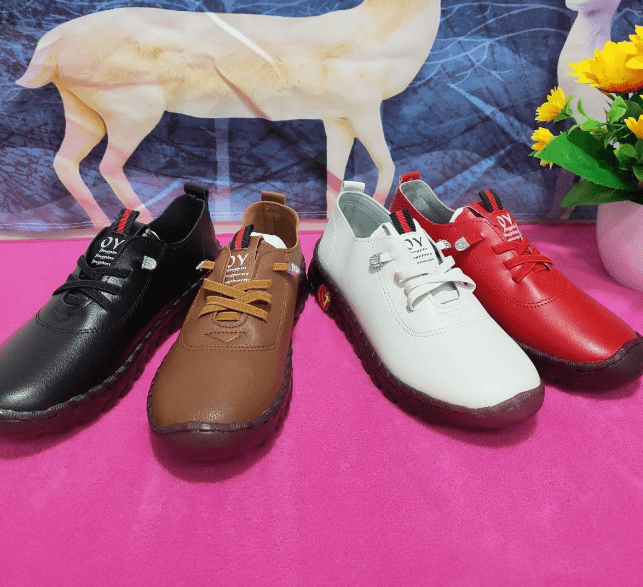 Vier Paar Freizeitschuhe in Schwarz, Braun, Weiß und Rot auf rosa Hintergrund mit Blumen.
