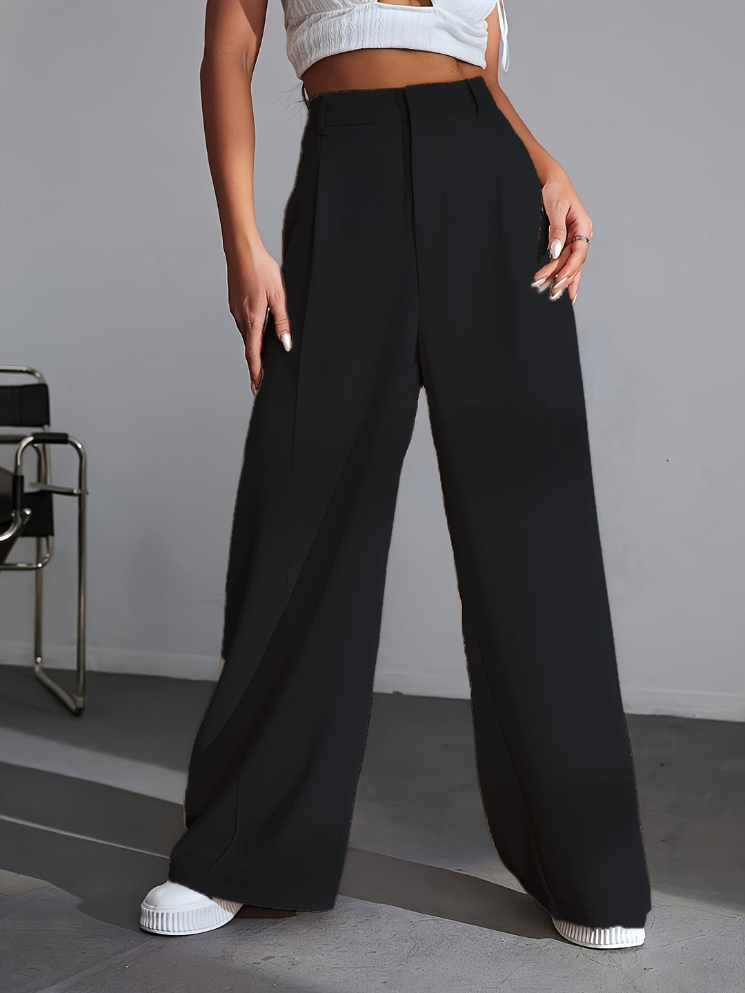 Frau in schwarzer, weiter Hose und weißem Top, modisch, elegant, moderne Damenmode.