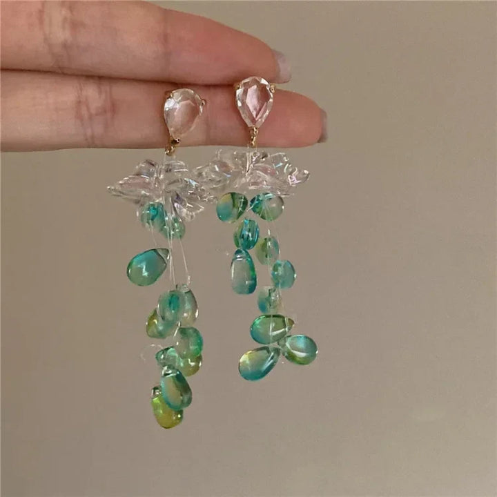 Handgefertigte Ohrringe mit grünen und blauen Perlen, transparentem Blüten-Design, elegant.