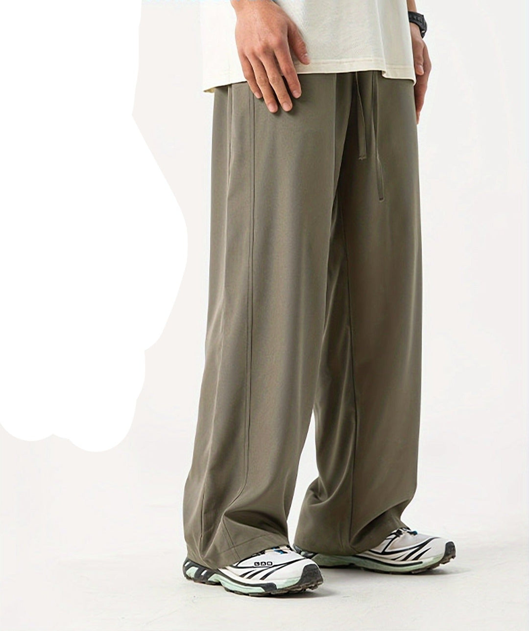Beige Herren-Jogginghose, locker geschnitten, aus Baumwolle, kombiniert mit weißen Sportschuhen.