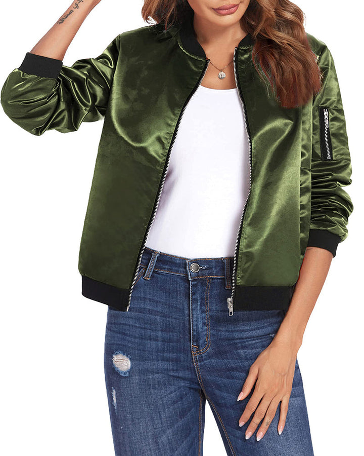 Frau trägt grüne Satin-Bomberjacke, weiße Bluse, blaue Jeans. Modische Damenbekleidung.