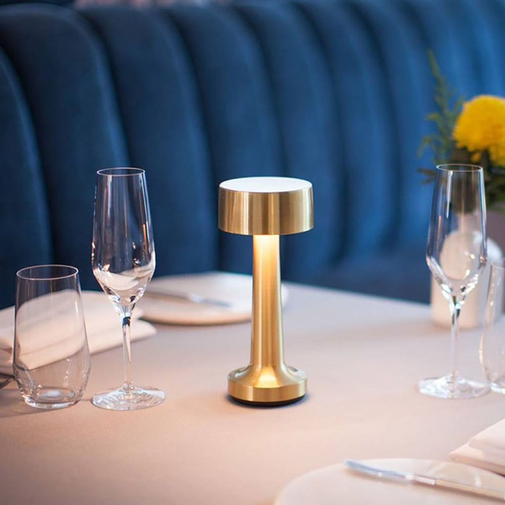 Goldene LED-Tischlampe auf gedecktem Tisch, modernes Design, ideal für stilvolle Beleuchtung.