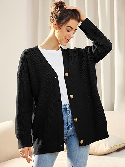 Frau trägt schwarzen Strickcardigan mit Knöpfen, weißes T-Shirt, blaue Jeans, lässiger Look.