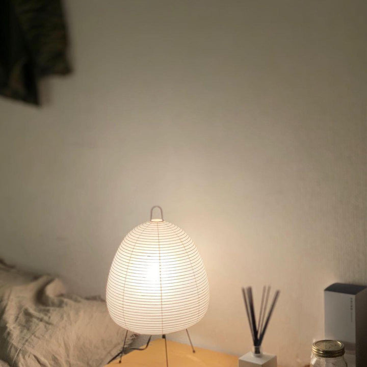 Weiße Akari Tischlampe auf Holzoberfläche, modernes Design, sanftes Licht, minimalistischer Stil.
