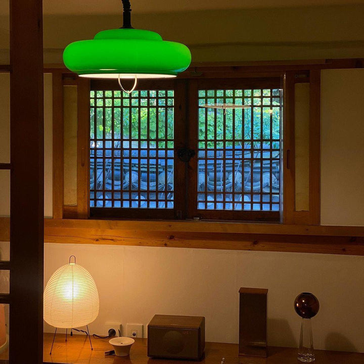Esstisch mit Akari Tischlampe, grünem Deckenlicht, Holzmöbeln, traditionellem Fenster im Hintergrund.