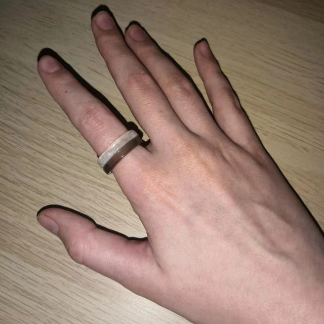 Hand mit Y2K-Stil Acrylharzring, beige, koreanische Mode 2023, auf Holzoberfläche.