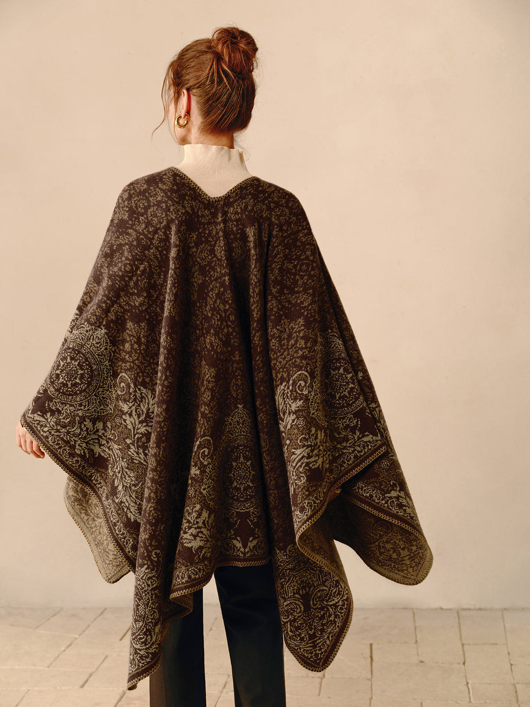 Frau trägt braunen Poncho mit Paisley-Muster, elegantes Herbstoutfit, Rückansicht.