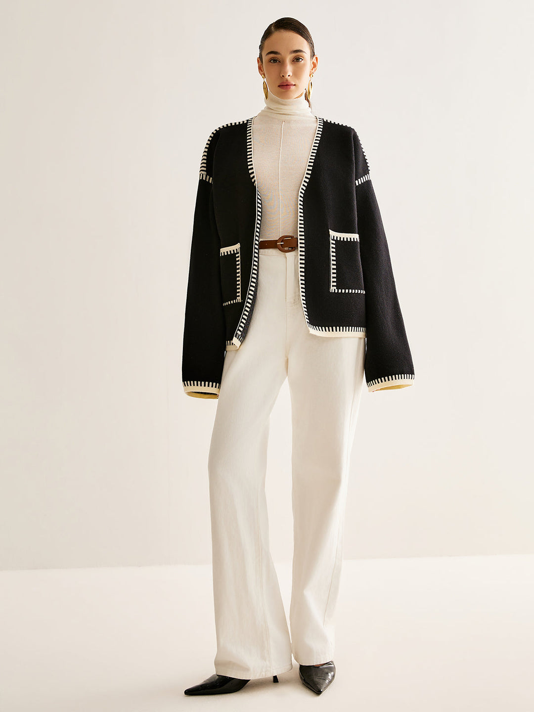 Frau in schwarzer Strickjacke und weißer Hose, elegantes Outfit, Mode, Damenbekleidung.