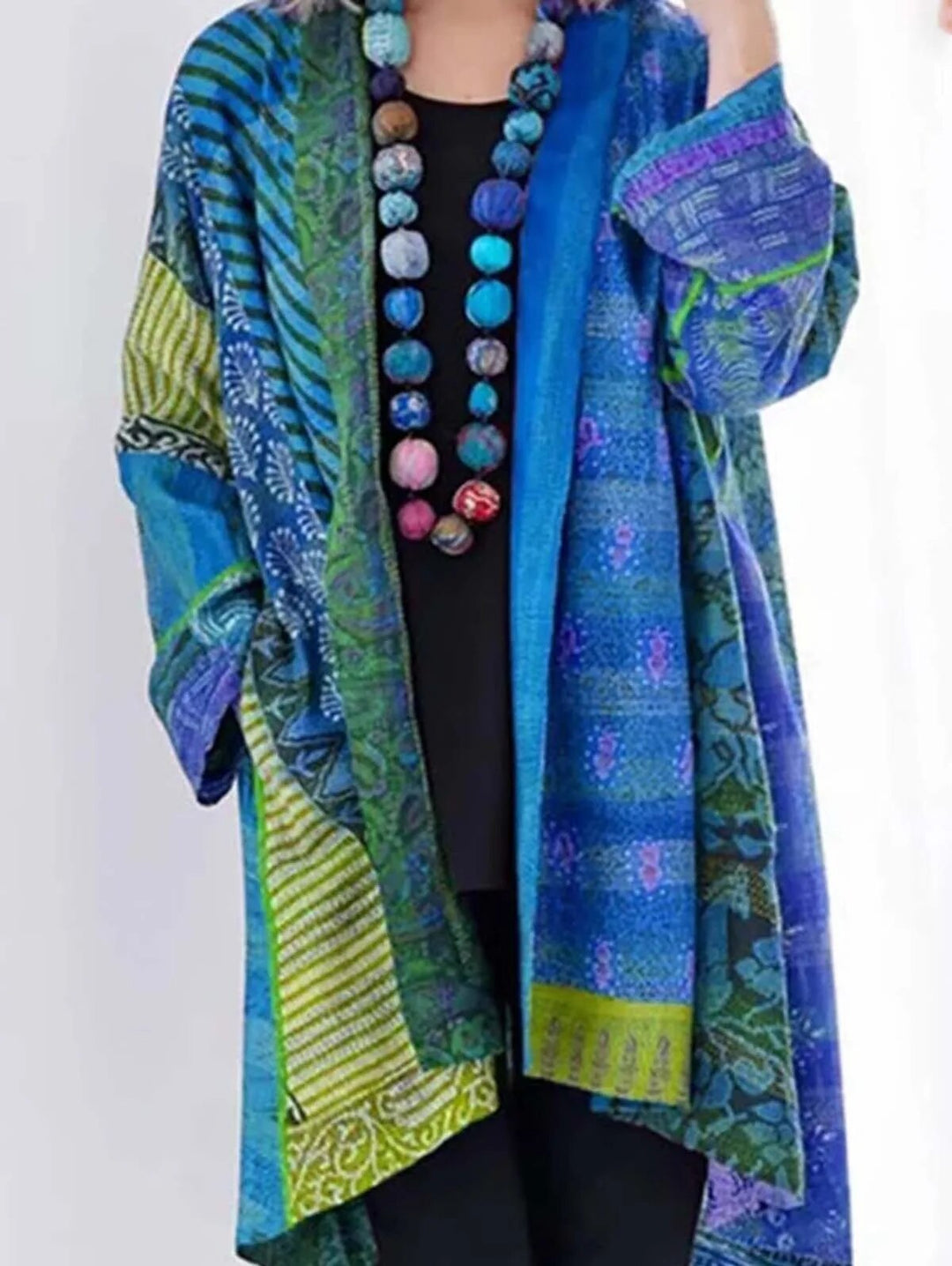 Frau trägt blau-grüne Patchwork-Strickjacke mit buntem Perlenhalsband, modisch, lässig.