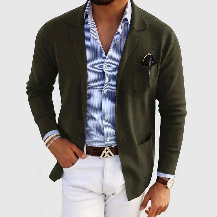 Herren Strickjacke in Olivgrün, kombiniert mit blau-weiß gestreiftem Hemd und weißer Hose.