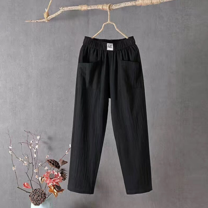Schwarze Damenhose aus Baumwolle, elastischer Bund, lässiger Stil, hängend an Ast.