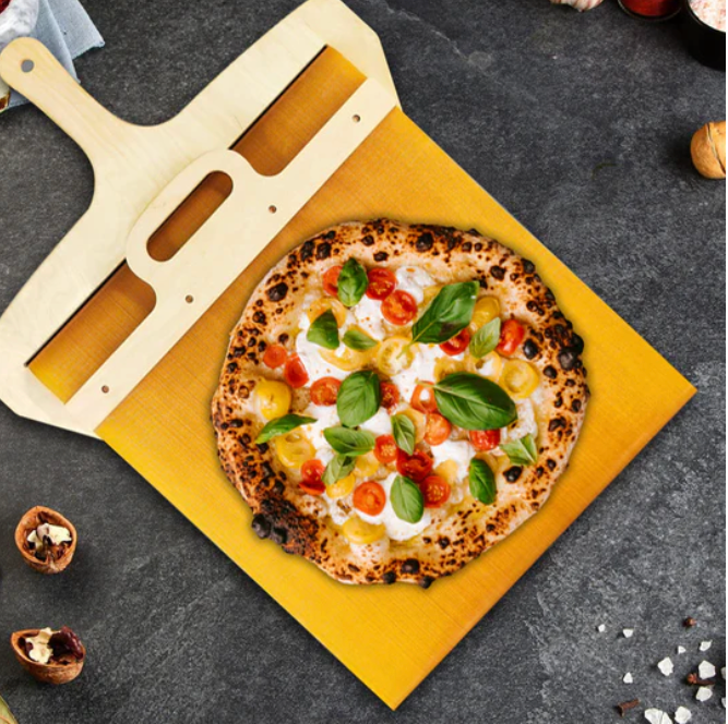 Holz-Pizzaschieber mit frischer Pizza, Tomaten, Basilikum auf grauem Hintergrund.