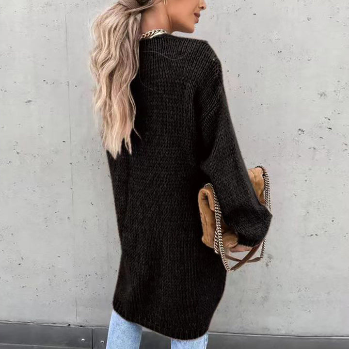 Frau in schwarzem Strickpullover, hellblaue Jeans, beige Tasche, lässiger Herbstlook.