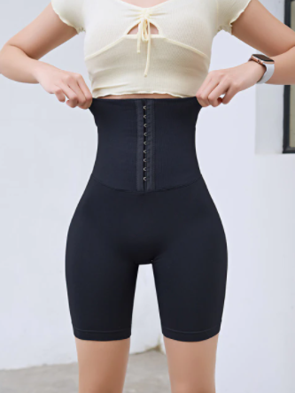 Frau trägt schwarze, hoch taillierte Shapewear-Shorts, figurformend, elastisch, bequem.