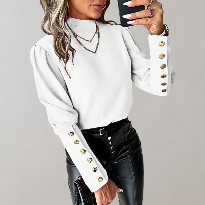 Frau in weißer Bluse mit goldenen Knöpfen, schwarze Lederhose, modisches Outfit.